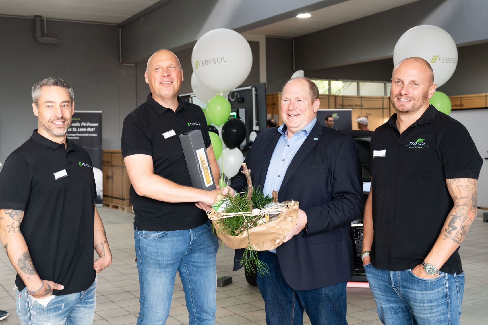 Vier M&auml;nner in schwarzen Hemden einer Photovoltaikanlage stehen nebeneinander.
