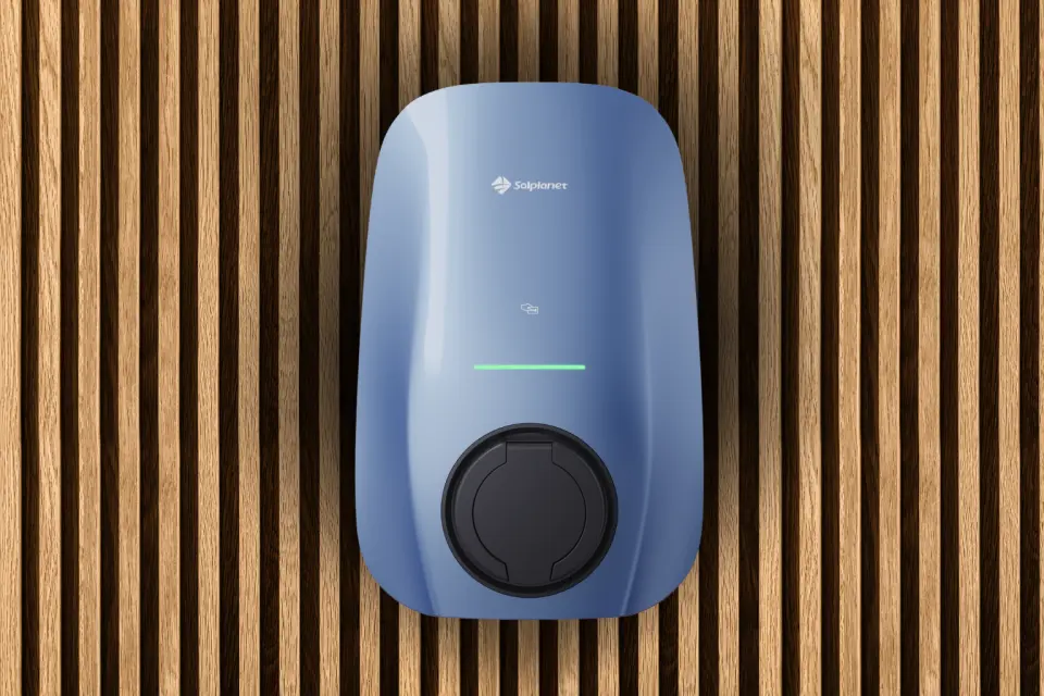 Eine blaue Ladestation für Elektrofahrzeuge, die an einer Holzlattenwand montiert ist.